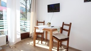 A dining area with a wooden table and chairs, a TV mounted on the wall, and a view of the outside balcony. - Apartment Liebl by Interhome (Seefeld in Tirol)