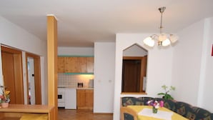 A compact living space with a dining area, kitchenette, and a sofa with a table set for two.