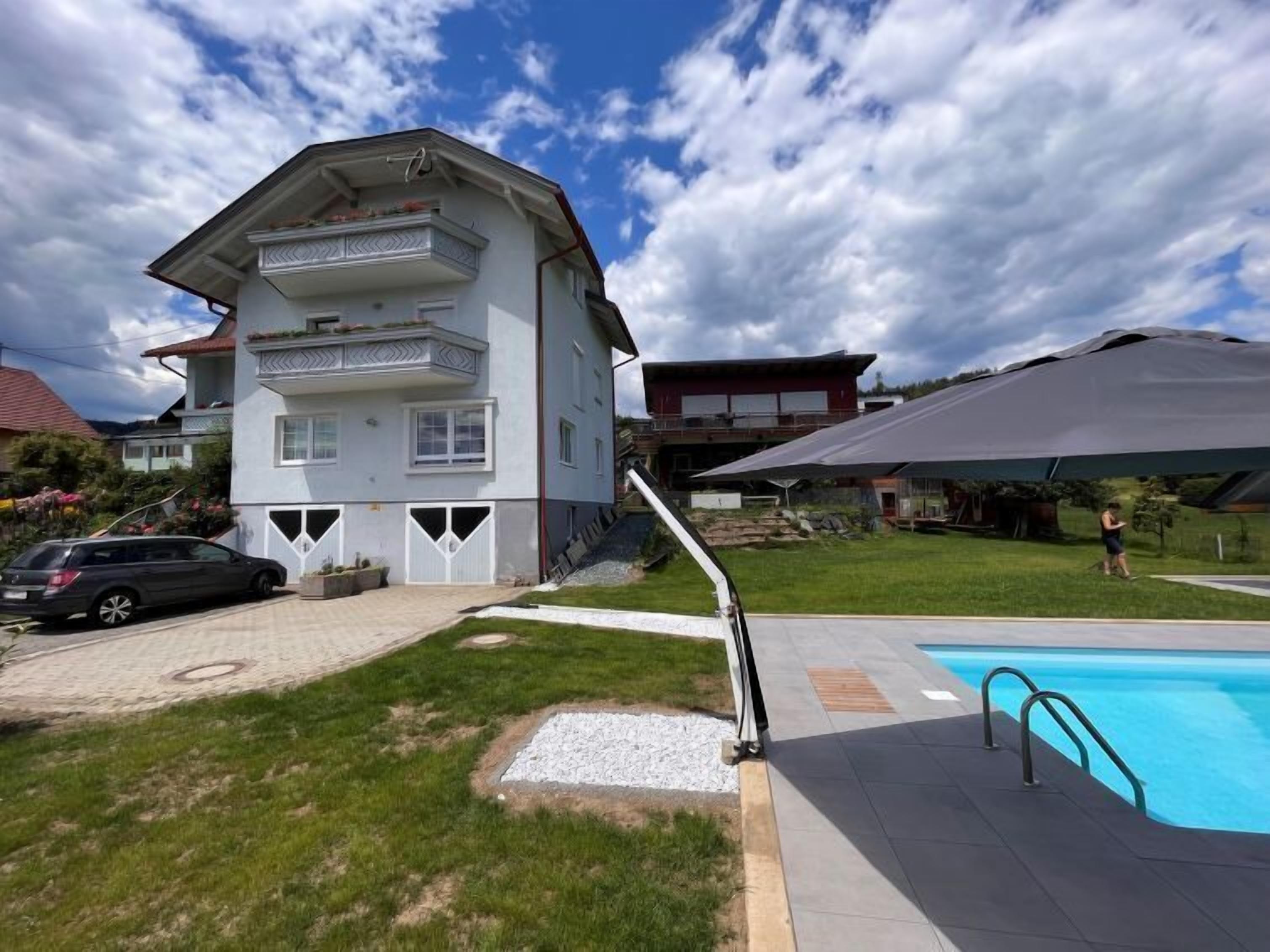 A two-story building with a balcony, a swimming pool, and a covered area.