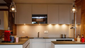 A modern kitchen with white cabinets, a stainless steel sink, and a red coffee machine. - Les Etoiles by Interhome (Nendaz)