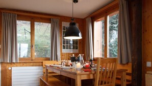 A wooden dining area with a table set for four, a bench, and a hanging light fixture. - Les Etoiles by Interhome (Nendaz)