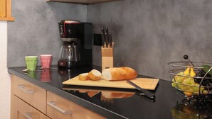 A kitchen with a coffee maker, a cutting board with bread and a knife, a fruit bowl, and a knife block. - Coucordin by Interhome (Nendaz)