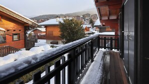 A wooden balcony with snow on the railings and ground, overlooking a snowy village with traditional buildings. - Coucordin by Interhome (Nendaz)
