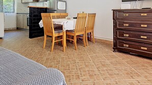 Una cocina compacta con una mesa de comedor, sillas, un refrigerador, un microondas y un televisor.
