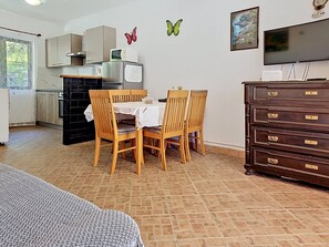 Une cuisine compacte comprenant une table à manger, des chaises, un réfrigérateur, un four à micro-ondes et un téléviseur.