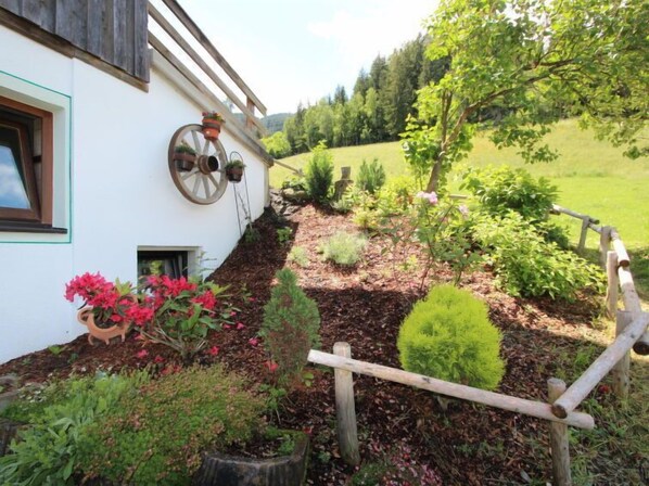 A rustic house with a garden featuring a wooden wheel, potted plants, and a variety of shrubs. - Annelies by Interhome (Aschau im Zillertal)