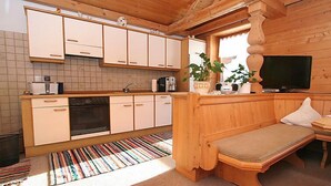 Uma cozinha compacta com armários brancos, forno embutido e um espaço de refeições com um banco.