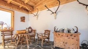 Uma zona de refeições rústica com soalho de pedra, mobiliário de madeira e decoração com chifres de veado.
