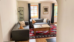 A living room with a grey sofa, a coffee table, and a patterned rug. There is a glass cabinet and a framed picture on the wall. - Dr.Steiner by Interhome (Zell am See)