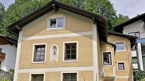 A two-story building with a textured facade, multiple windows, and a small statue on the second floor. - Dr.Steiner by Interhome (Zell am See)