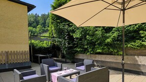 Une terrasse extérieure aménagée avec des meubles en osier, une table et un grand parasol.