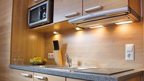 A modern kitchen with wooden cabinets, a granite countertop, a built-in microwave, and under-cabinet lighting. - Bella Monte by Interhome (Pettneu am Arlberg)