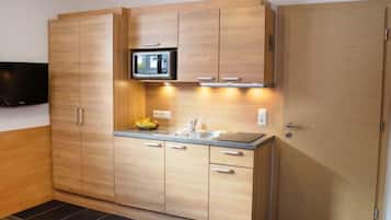 Een koelkast, een microgolfoven, kookgerei, borden en bestek