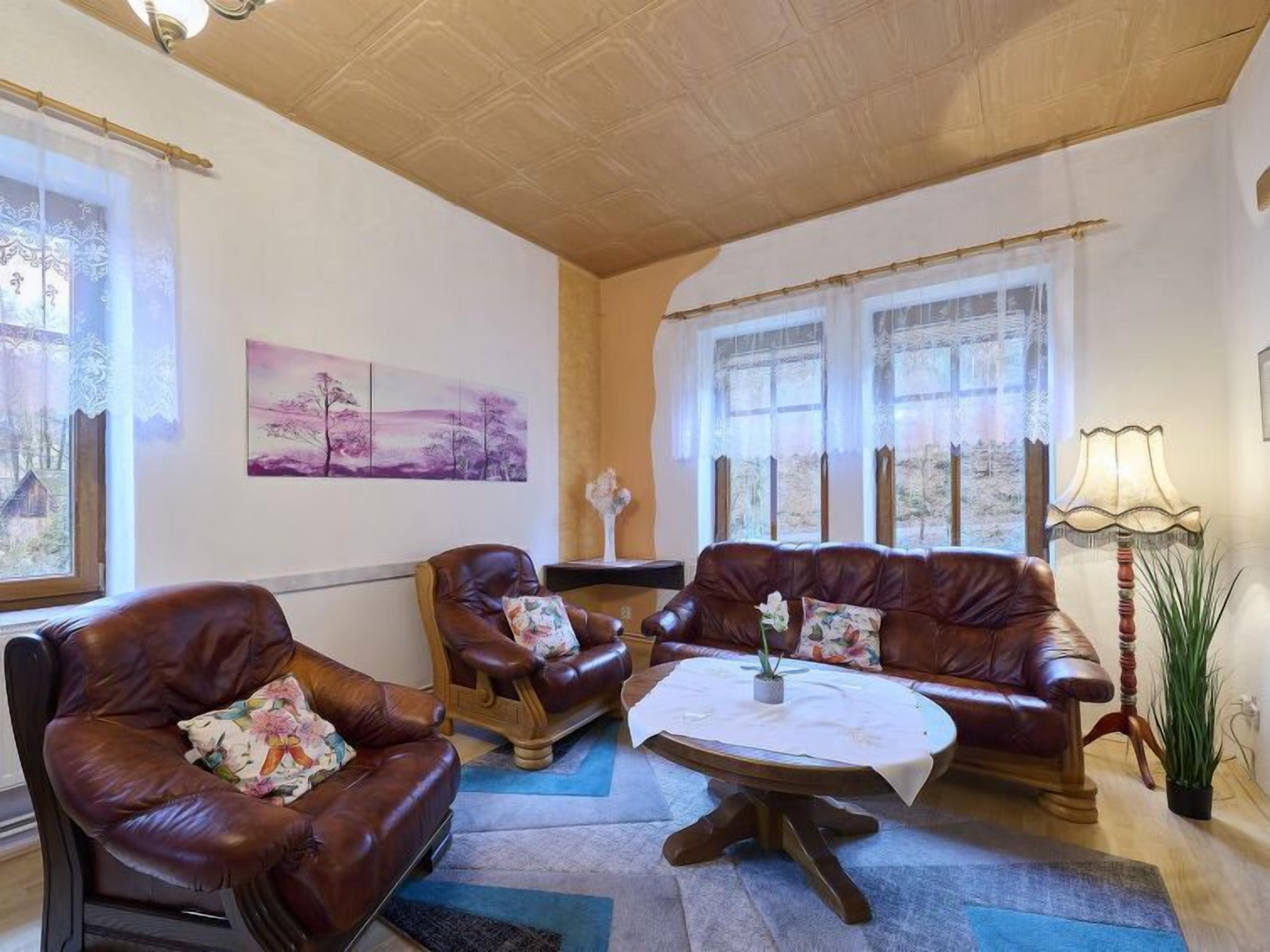 Un salon chaleureux avec des canapés en cuir, une table basse ronde et une lampe.