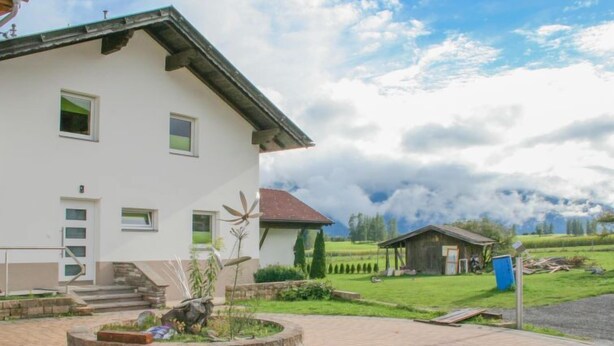 Ein modernes, zweistöckiges Haus mit einer kreisrunden Auffahrt und einem kleinen Garten.