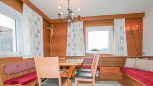 Ein gemütlicher Raum mit Holzmöbeln, einer Bank, einem Tisch und einem Chandelier.