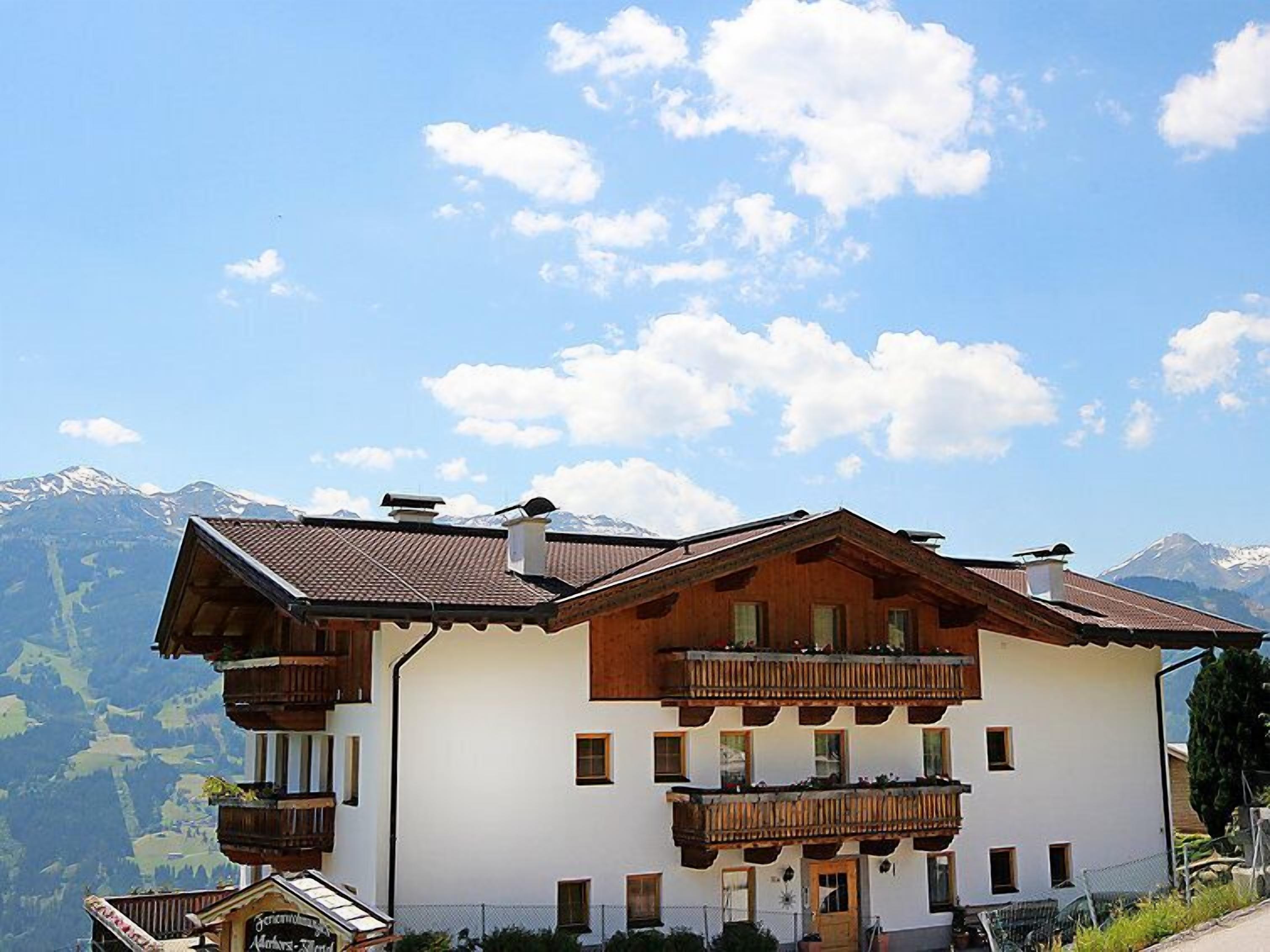 A two-story building with wooden balconies and a mountain backdrop.