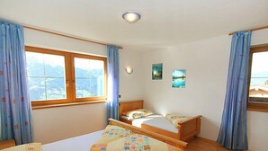 Une chambre avec deux lits, une fenêtre avec des rideaux et une vue sur l’extérieur.