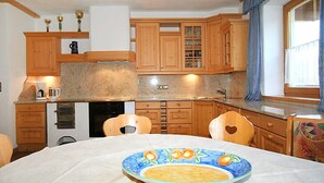 Une cuisine compacte avec des meubles en bois, un four encastré et une table à manger agrémentée d’une assiette décorative.