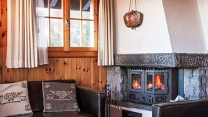 A cozy room with a stone fireplace, wooden walls, and a leather sofa with decorative pillows. - Magicien by Interhome (Nendaz)