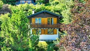 A wooden cabin with a balcony, surrounded by dense forest and other cabins. - Magicien by Interhome (Nendaz)