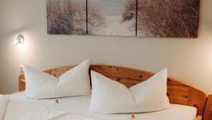 A bedroom with a wooden headboard, white bedding, and a beach-themed wall art above the bed. - Apartment Rosi by Interhome (Werfenweng)