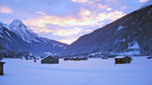 Un valle cubierto de nieve con cabañas de madera y montañas al fondo.