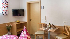 Una habitación de hotel con cama, escritorio, silla, televisor y puerta.