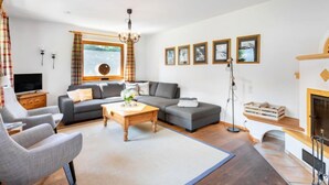 Ein modernes Wohnzimmer mit einer Couch, Sesseln, einem Couchtisch und einem Kamin.