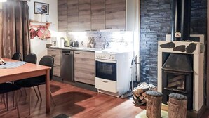 Une cuisine de taille réduite, dotée de meubles en bois, d’une cuisinière et d’une cheminée.