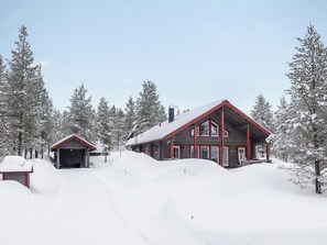 A two-story log cabin with a red roof, surrounded by snow-covered trees. - Kerkänperä by Interhome (Sodankylä)