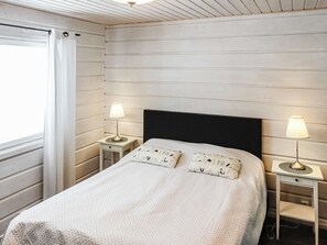 A bedroom with a bed, two bedside tables, two lamps, and a window with curtains. - Kerkänperä by Interhome (Sodankylä)