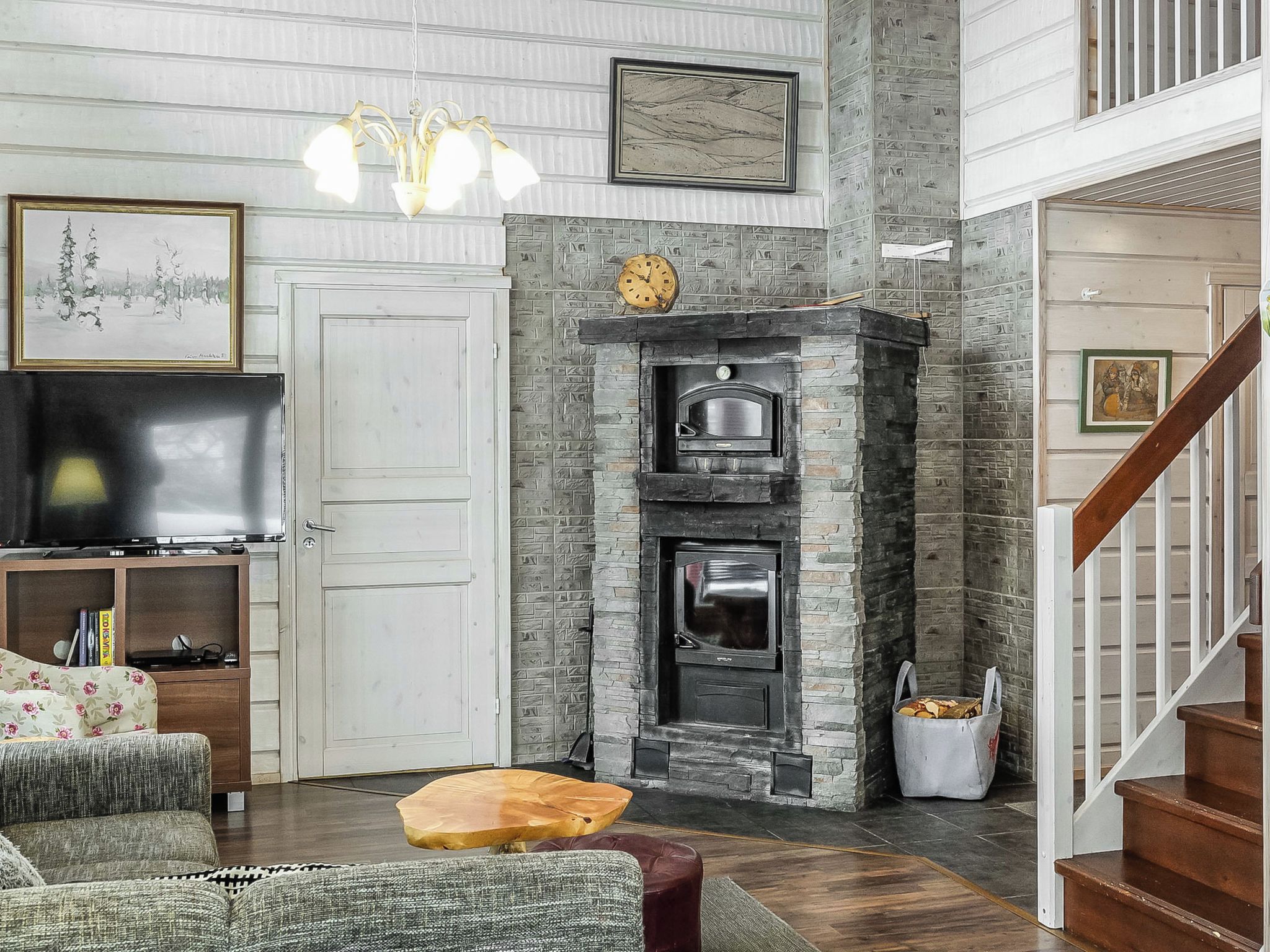 Una sala de estar con chimenea, televisor y escalera.