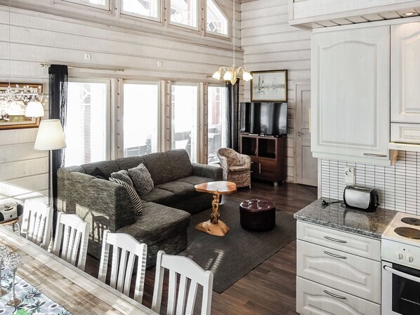 A spacious living area with a sofa, armchairs, a coffee table, and a dining table. There is a kitchen with a toaster and a stove.