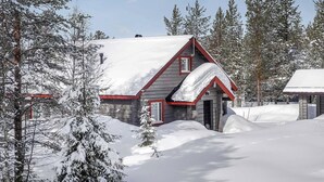 A cabin with a red roof and stone walls, surrounded by snow-covered trees. - Kerkänperä by Interhome (Sodankylä)
