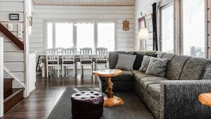 A spacious living room with a gray sofa, a wooden coffee table, and a dining area with white chairs. - Kerkänperä by Interhome (Sodankylä)
