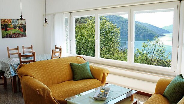 Un salón acogedor con un sofá, una mesa de centro y vistas a un lago y montañas.