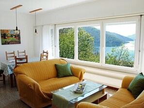 Un salón acogedor con un sofá, una mesa de centro y vistas a un lago y montañas.