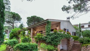 A house with a stone foundation, a covered porch, and a staircase leading to the entrance. - Hermine by Interhome (L'Escala)