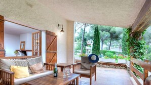 A cozy patio with wooden furniture, a table, and a bottle of wine. - Hermine by Interhome (L'Escala)