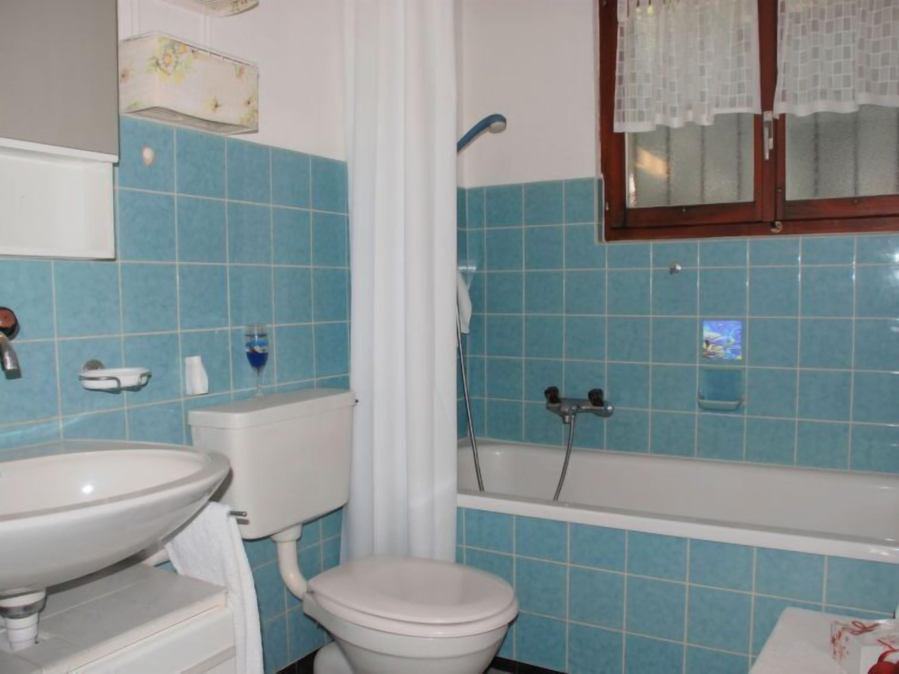 Un baño con inodoro, lavamanos y bañera.