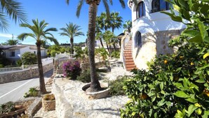 A Mediterranean-style building with a stone pathway, palm trees, and a clear blue sky. - Roberto by Interhome (Benissa)