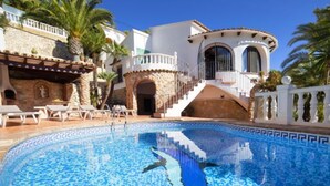 A swimming pool with a mosaic design, surrounded by palm trees and a white building with a curved balcony. - Roberto by Interhome (Benissa)