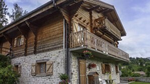 A traditional chalet with a stone facade, wooden balconies, and a stone entrance. - Namasté by Interhome (Le Grand Bornand)