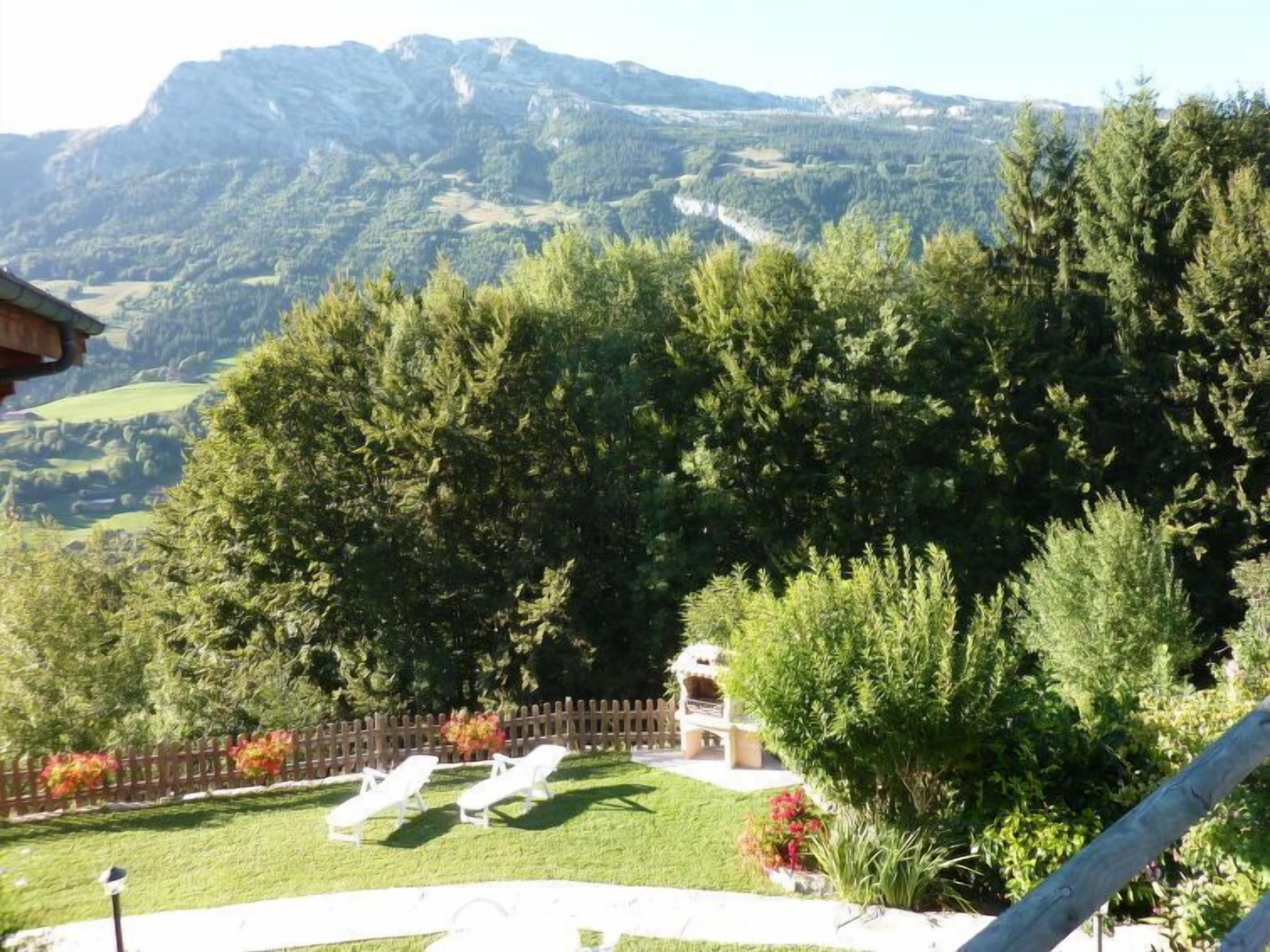 Vista de un paisaje montañoso con un césped y dos sillones blancos.