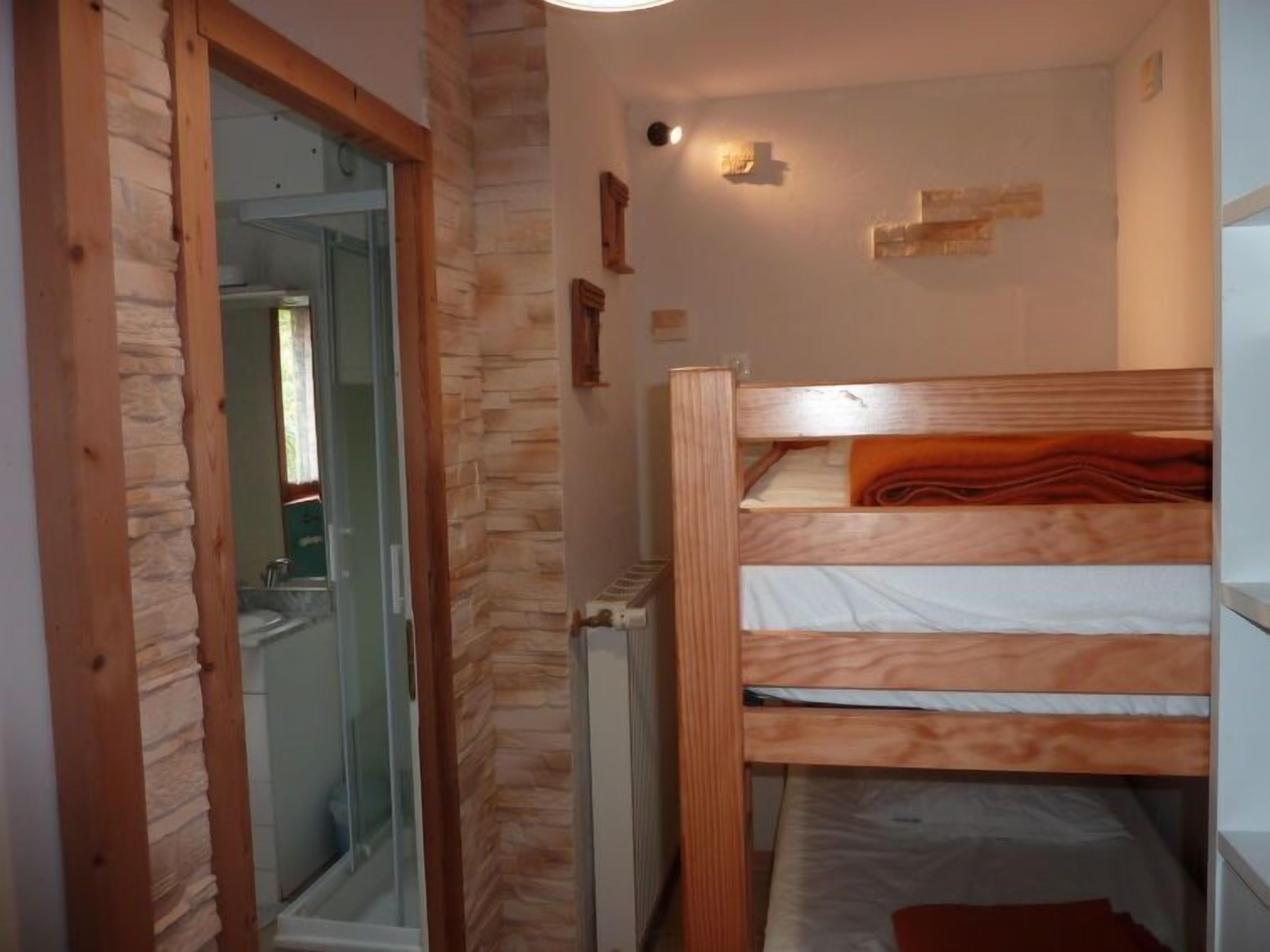 A small, cozy room with a bunk bed, a wooden door, and a radiator.