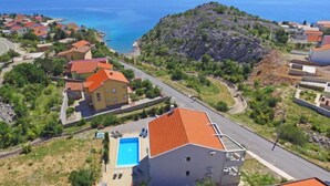 A residential area with houses, a swimming pool, and a view of the sea. - Apartment Sani by Interhome (Karlobag)