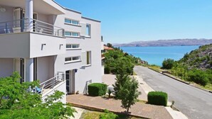 A modern two-story building with balconies, a paved driveway, and a view of a lake. - Apartment Sani by Interhome (Karlobag)