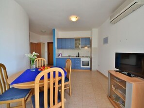 Un espace de vie compact comprenant un coin repas, une kitchenette et un téléviseur.