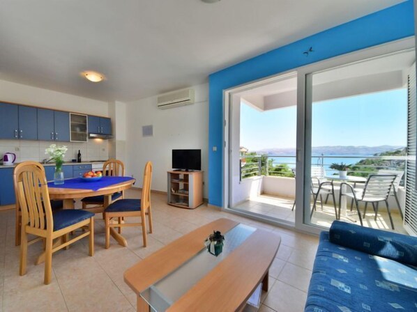 Un appartement moderne doté d’un coin repas, d’une télévision et d’un balcon avec vue.